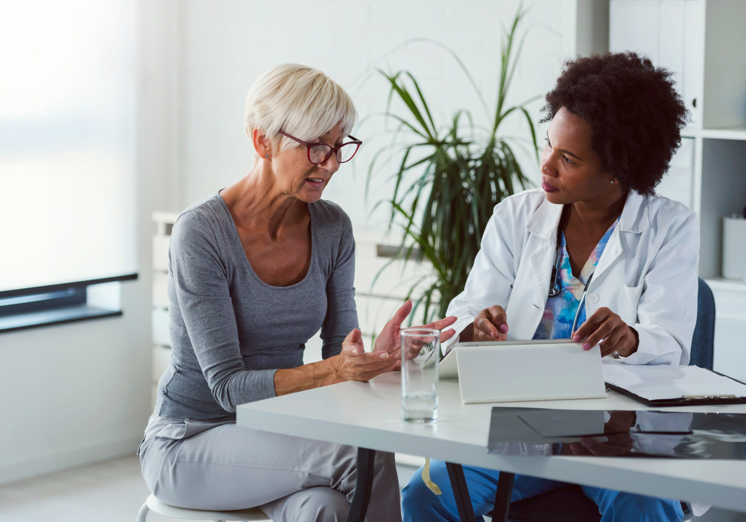 Two women sitting at a table with laptops.